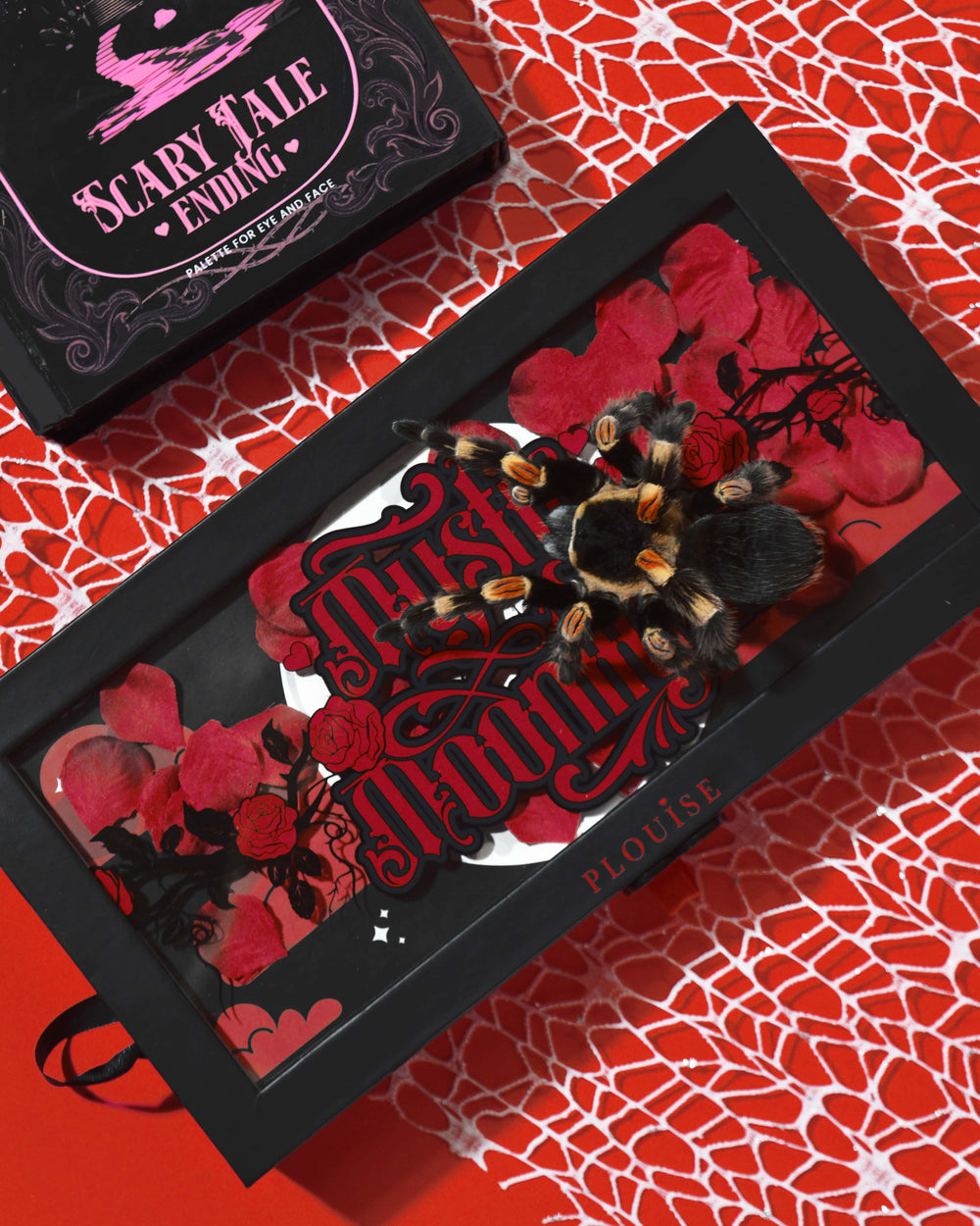 P.Louise Mystic Moonlight Halloween Eyeshadow Palett box täckt av röda rosenblad och en tarantula på en röd spindelnätbakgrund