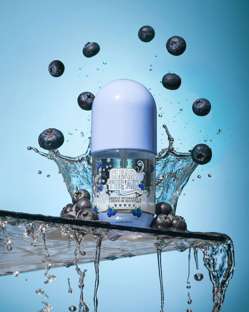 Flaska P. Louise Clear The Air Blueberry Gel Cleanserl omgiven av blåbär och vattenstänk på en blå bakgrund
