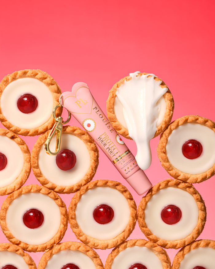 Rosa körsbärsmandel doftande tonat skydda din pout läppbalsam med guldklämma placerad mellan körsbärsbakewell desserter