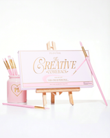 A closed pink P.Louise Creative Comeback XXXL Rainbow Eyeshadow Palette placed on an art easel surrounded by makeup brushes