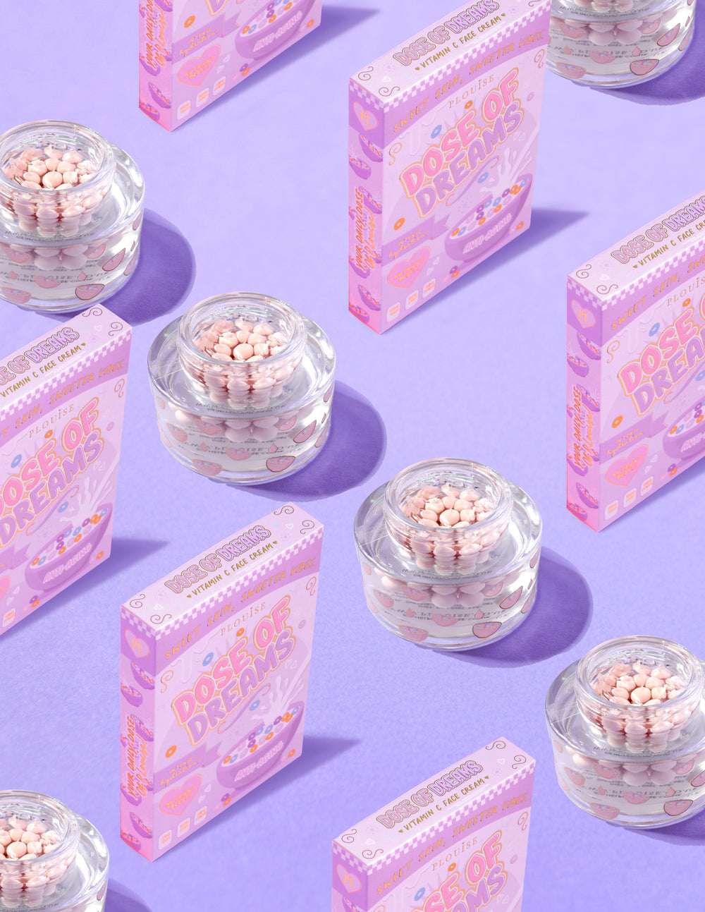 Klara behållare med P.Louise DOse of Dreams Vitamin C Capsule Face Cream med rosa kapsel i dem omgivna av rosa flingslådor på en lila bakgrund