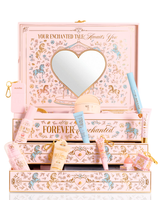 A P.Louise pastellrosa, blå och gul jul PR skönhetspresentförpackning märkt "Your Enchanted Tale" med en hjärtformad spegel på locket och öppna lådor, omgiven av diverse kosmetiska tuber, flaskor och en liten påse på en vit bakgrund.