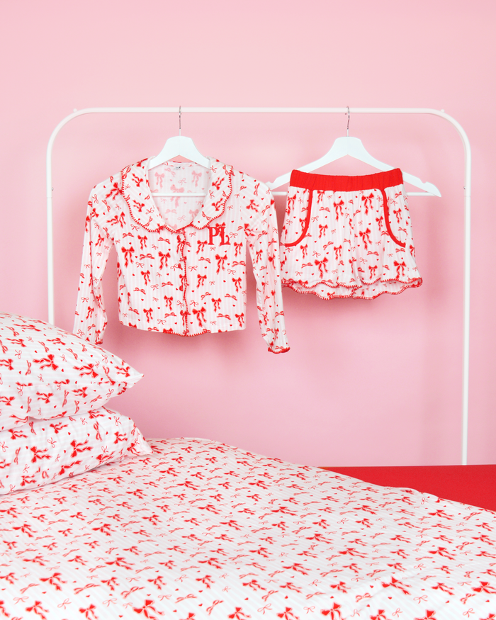 Set med rosa och vitrandiga tjejer P.Louise julrosett pyjamasshorts på galgar i ett rosa sovrum med matchande sängkläder 
