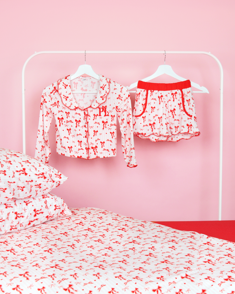 Set med rosa och vitrandiga tjejer P.Louise julrosett pyjamasshorts på galgar i ett rosa sovrum med matchande sängkläder 