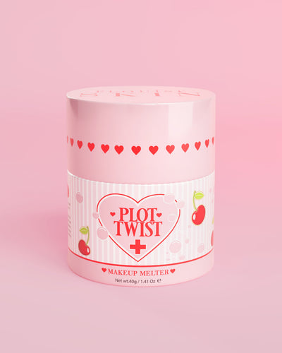 En rosa behållare med P.Louise Plot Twist Makeup Melting Cleansing Balm med hjärta och körsbärsmönster på etiketten mot en rosa bakgrund
