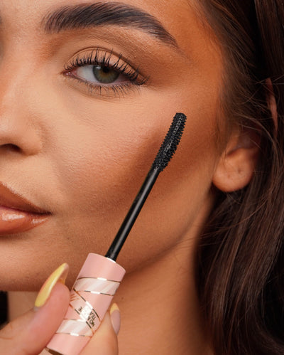 Närbild av en P.Louise Tearproof mascara trollstav som hålls nära en persons öga med suddig bakgrund