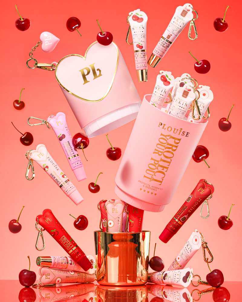Pink XL Protect Your Pout Gift Set som öppnas omgiven av körsbär och rosa och röda läppbalsam på en rosa bakgrund