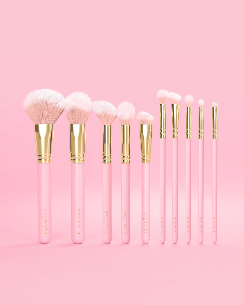 Set med 10 rosa P.Louise sminkborstar med rosa handtag och gulddetaljer på en rosa bakgrund