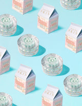 Klara behållare med P.Louise Dose of Dreams Vitamin C Capsule Cream med blå kapsel inuti dem omgivna av mjölkkartonger