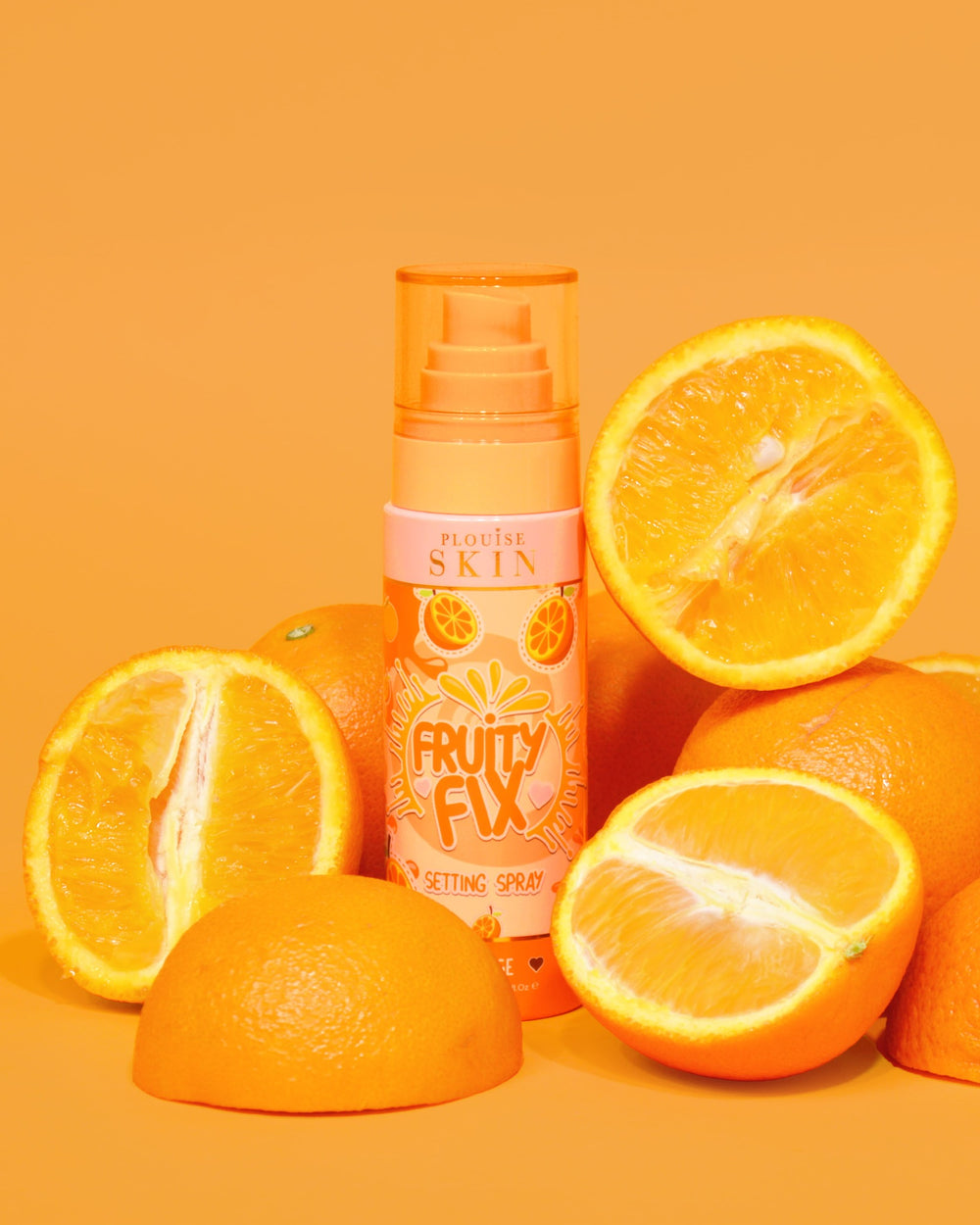 En orange flaska P. Louise Fruity Fix Vitamin C Setting Spray med en orange bakgrund omgiven av färska apelsinskivor.