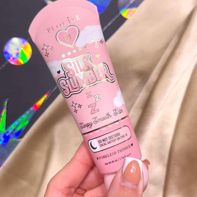 En person som håller en tub P.Louise Silk Slumber Poreless Primer med en rosa bakgrund och kosmetiska produktdetaljer.
